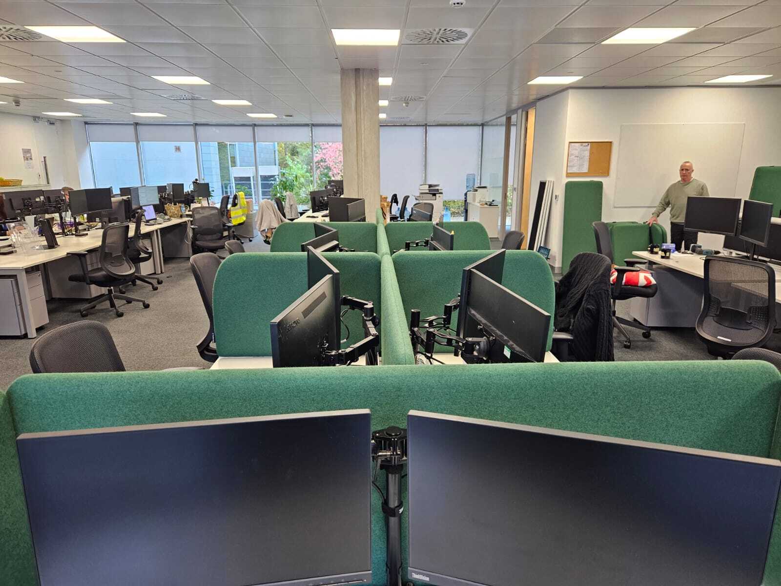 Green acoustic desk screens fitted across two banks of desks at Vorwerk